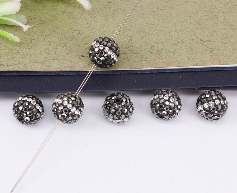 May include: Six black and silver round beads with a sparkly finish. The beads are strung on a silver wire.