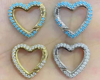 Könnte beinhalten: Vier herzförmige Verschlüsse mit einem dekorativen Design. Zwei Verschlüsse sind golden mit klaren Steinen und zwei sind silber mit blauen Steinen.