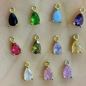 May include: Twelve gold teardrop-shaped charms with different coloured gemstones. The charms are perfect for jewellery making and crafting.
