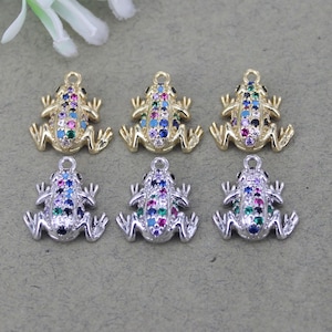 May include: Six frog charms with colorful rhinestones. Three charms are gold-toned and three are silver-toned.