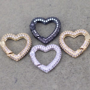 May include: Four heart-shaped clasps with a sparkly, crystal-like finish. The clasps are in silver, gold, and black.