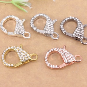 May include: Five silver, gold, and gunmetal lobster clasps with clear rhinestone embellishments.