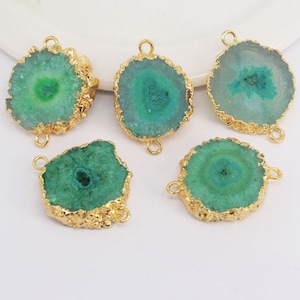 May include: Five green agate gemstone connector charms with gold-plated edges and two jump rings. The agate is a light green color with a darker green center.