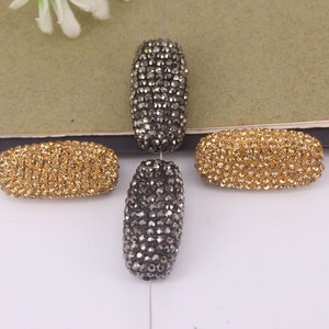 May include: Four oval-shaped rhinestone beads, two are gold and two are black.
