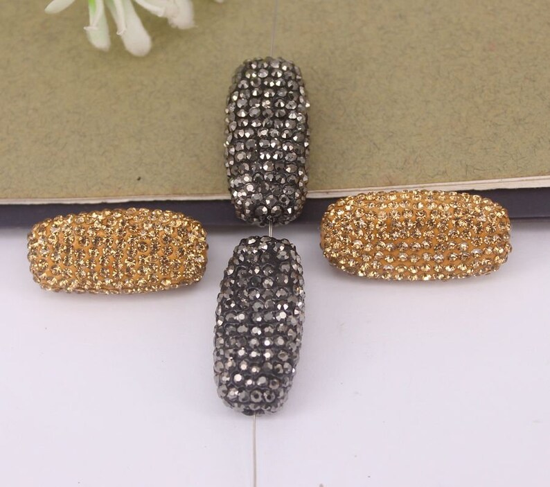 May include: Four oval-shaped rhinestone beads, two are gold and two are black.