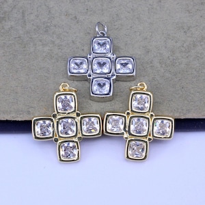 May include: Three cross pendants. One is silver-toned, and the other two are gold-toned. Each cross features five square, clear, sparkling stones. The pendants are designed for jewelry making or as decorative elements.