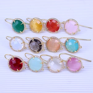 May include: Assortment of 10 pairs of gold tone earrings with a round faceted gemstone and a clear crystal halo. The gemstones are in various colors including green, yellow, red, pink, white, gray, peach, turquoise, burgundy, and light blue.