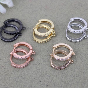 May include: Six pairs of hoop earrings with a clear crystal embellishment. The hoops are available in black, gold, rose gold, and silver.