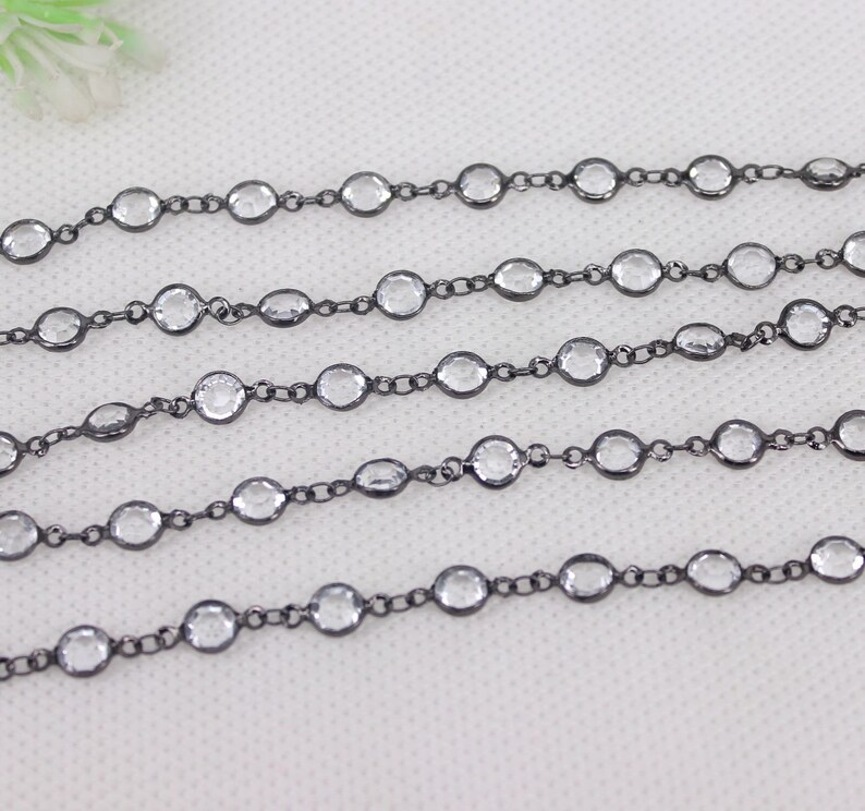 May include: A black chain with clear faceted beads. The chain is made of metal and is approximately 18 inches long.