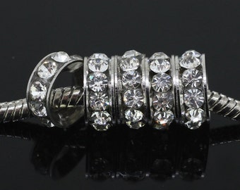 May include: A silver charm bracelet with a silver spacer bead featuring multiple rows of clear rhinestones.