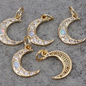 May include: Five gold crescent moon charms with opal stones and clear rhinestones. The charms have a textured surface and are perfect for jewelry making.