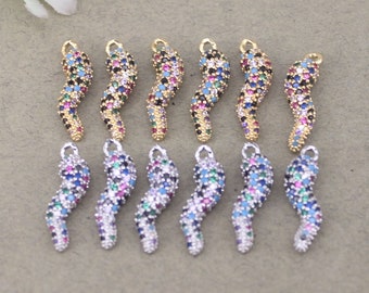Puede incluir: Un conjunto de 12 colgantes de amuleto de oro y plata con forma de cuerno curvado, cada uno adornado con piedras de circonita cúbica de colores.