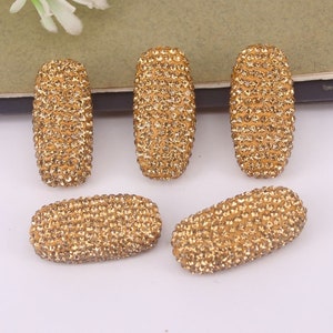 May include: Six gold oval-shaped embellishments covered in small, sparkling rhinestones.