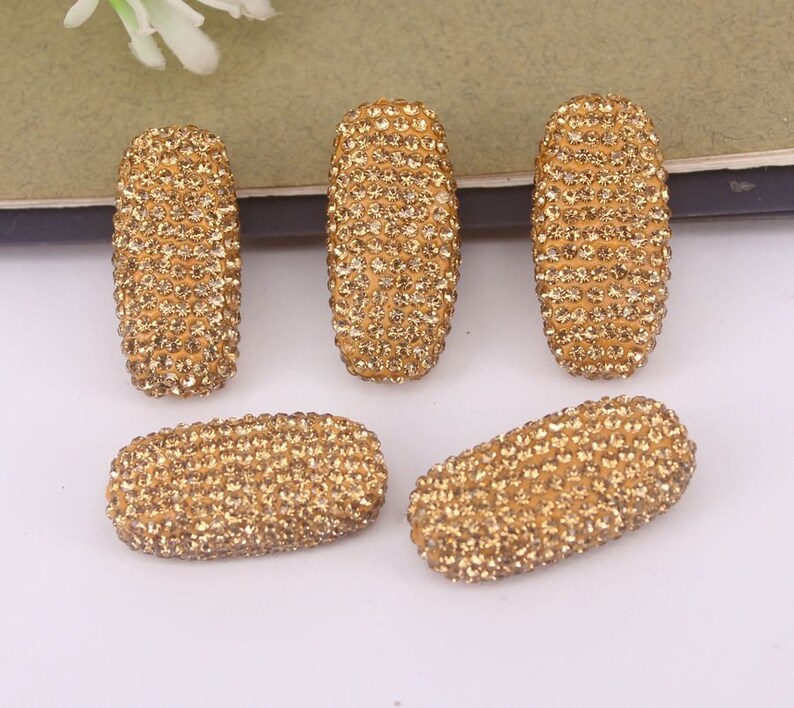 May include: Six gold oval-shaped embellishments covered in small, sparkling rhinestones.