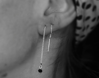 May include: A pair of silver chain earrings with a black bead on one and a silver bar on the other.