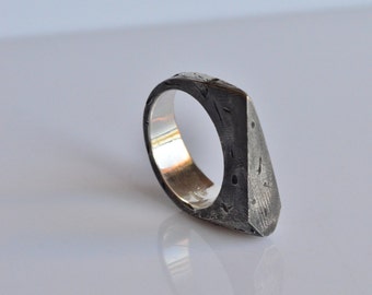 May include: A silver ring with a textured, triangular face. The ring is made of metal and has a polished silver band.