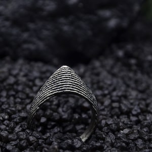 Könnte beinhalten: Ein silberner Ring mit einem strukturierten, geometrischen Design. Der Ring ist aus Metall und hat eine glatte, polierte Oberfläche.