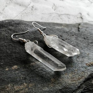 Puede incluir: Un par de pendientes de plata con puntas de cristal de cuarzo transparente. Los cristales son largos y delgados, y los pendientes tienen un dise&ntilde;o simple y minimalista.