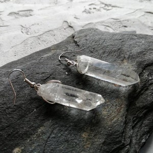 Puede incluir: Un par de pendientes de plata con puntas de cristal de cuarzo transparente. Los cristales son largos y delgados, y est&aacute;n suspendidos de los pendientes mediante un simple bucle de alambre.