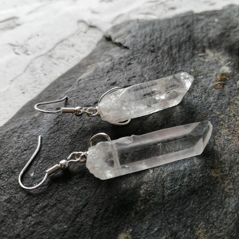 Puede incluir: Un par de pendientes de plata con colgantes de cristal de cuarzo transparente. Los cristales son largos y delgados, con una punta puntiaguda.