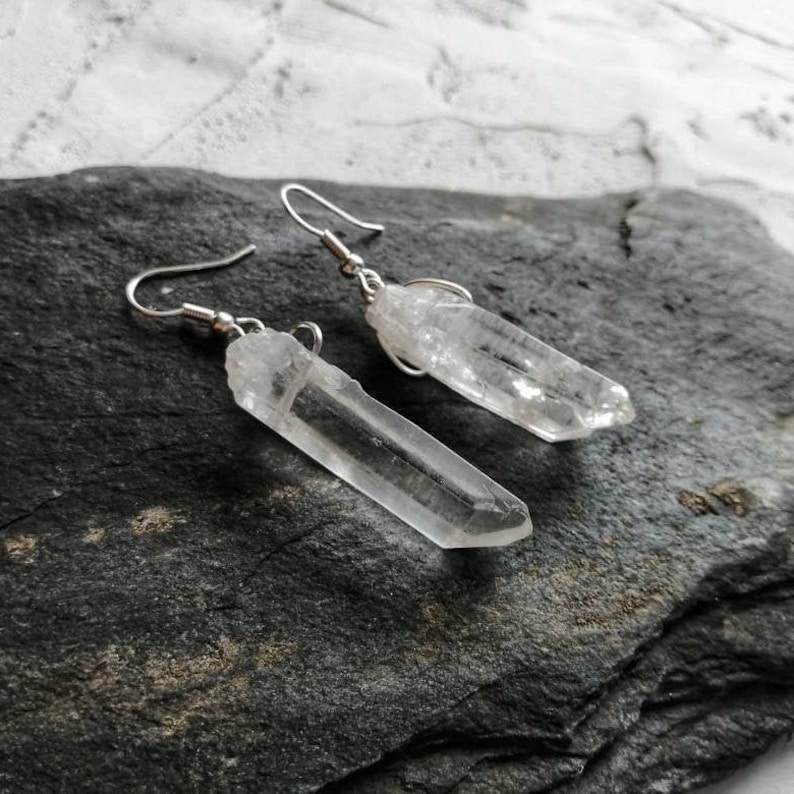 Puede incluir: Un par de pendientes de plata con puntas de cristal de cuarzo transparente. Los cristales son largos y delgados, y los pendientes tienen un dise&ntilde;o simple y minimalista.