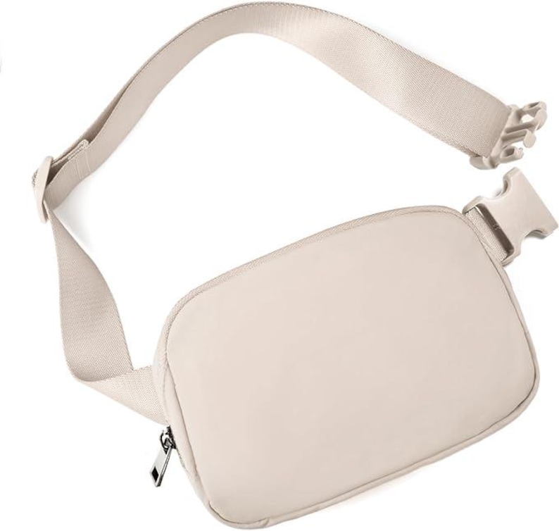 May include: A beige fanny pack with an adjustable strap and a plastic buckle closure. The pack has a rectangular shape with a zippered main compartment. The strap is made of a matching beige material.