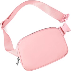 May include: A light pink fanny pack with a matching adjustable strap and buckle closure. The bag features a zippered main compartment and a sleek, minimalist design. The strap is approximately 40 inches long.