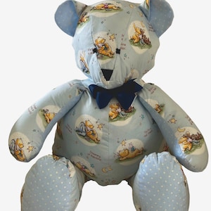 May include: A blue and white stuffed teddy bear with a blue bow tie. The bear is covered in a Winnie the Pooh print with stars and the text "It's time to relax", "You're a real friend", and "Dreaming of wonderlands".