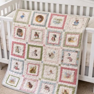 May include: A patchwork quilt featuring square panels with illustrations of animals in various scenes. The quilt has a white background with pink, green, and blue borders. The quilt is draped over a white crib.