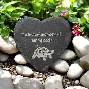 May include: A heart-shaped slate stone memorial with the inscription "In loving memory of Mr Speedy" and a carved image of a tortoise.