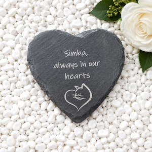 May include: A heart-shaped dark grey slate plaque featuring the engraved text Simba, always in our hearts and a line art illustration of a cat head forming a heart shape. The plaque has a rough, natural stone texture and uneven edges.