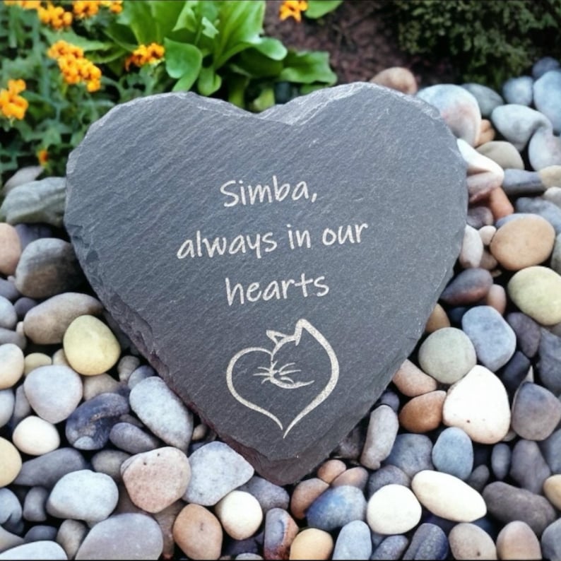 May include: A gray heart-shaped slate stone memorial with the inscription "Simba, always in our hearts" and a stylized cat sleeping in a heart.