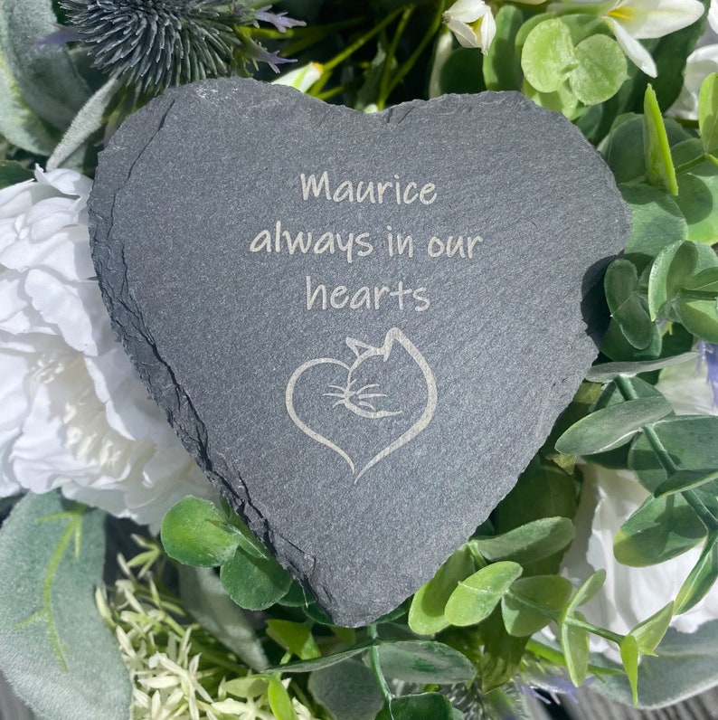 May include: A gray heart-shaped slate stone with the inscription "Maurice always in our hearts" and a stylized cat silhouette.