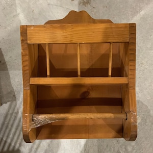 May include: A wooden wall-mounted shelf with a towel rack underneath. The shelf has a decorative top edge and is made of natural wood.