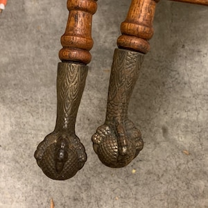 May include: Two wooden furniture legs with decorative brass claw feet. The legs are turned and have a fluted design.