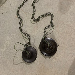 May include: Two black metal ceiling light fixtures with a chain and green wire hanging from each.
