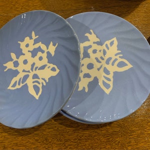 May include: Four blue ceramic plates with a white snowflake design. The plates have a textured surface and are perfect for serving desserts or snacks.