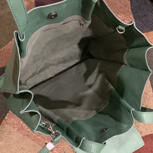 Puede incluir: Vista abierta de un bolso tote de cuero verde con una bolsa desmontable a juego. El bolso tiene dos asas y un cierre magn&eacute;tico a presi&oacute;n. El interior es de un tono verde m&aacute;s claro.