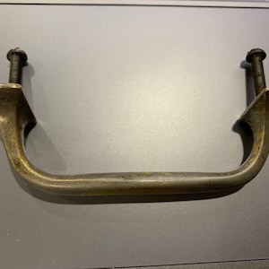 May include: A vintage brass handle with two screws. The handle is curved and has a smooth, aged finish.
