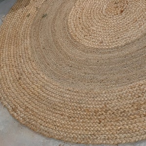May include: A round, natural fiber rug with a woven texture. The rug is made of jute and has a light brown color.