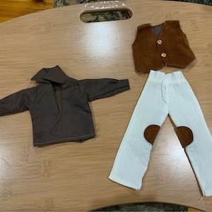 May include: A brown long-sleeved shirt, white pants with brown knee patches, and a brown vest with a gold button.