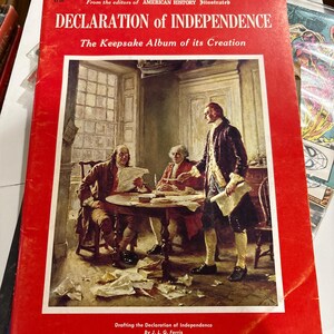 May include: A red book titled "DECLARATION of INDEPENDENCE" with an illustration of men drafting the document. The book is part of the "AMERICAN HISTORY Illustrated" series. The cover features the text "The Keepsake Album of its Creation" and "SECOND EDITION".