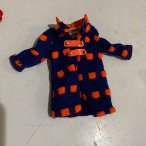 May include: A blue and orange polka dot doll coat with gold buttons and the text "Skipper" and "Playmate" on the collar.
