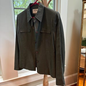 May include: A dark green blazer with a button-up front and a single pocket on each side. The blazer has a label that reads "Koper KSL".