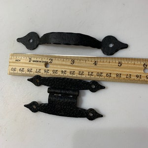 May include: Two black metal door hinges with a decorative pointed design. The hinges are approximately 3 inches long and have a hammered finish.