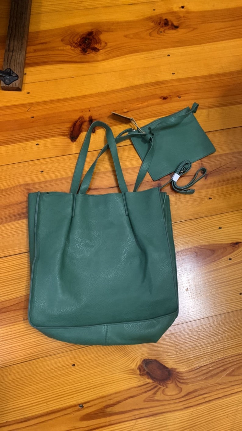 Puede incluir: Un conjunto de bolso tote y bandolera a juego de color verde. El bolso tote tiene asas largas y un compartimento principal grande. El bolso bandolera tiene una correa para el hombro. Ambos bolsos est&aacute;n hechos de un material texturizado.