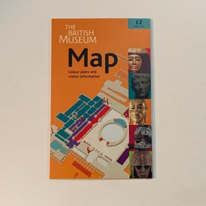 May include: A map of the British Museum with a floor plan and visitor information. The map is orange and features images of ancient artifacts. The text on the map reads "The British Museum Map, Colour plans and visitor information, £2 English."