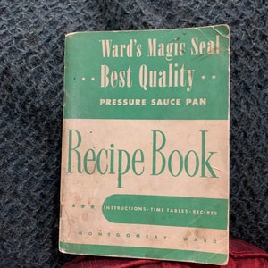 May include: A green and white vintage cookbook titled "Ward's Magic Seal - Best Quality - Pressure Sauce Pan Recipe Book" with the text "INSTRUCTIONS - TIME TABLES - RECIPES" and "MONTGOMERY WARD" printed on the cover.