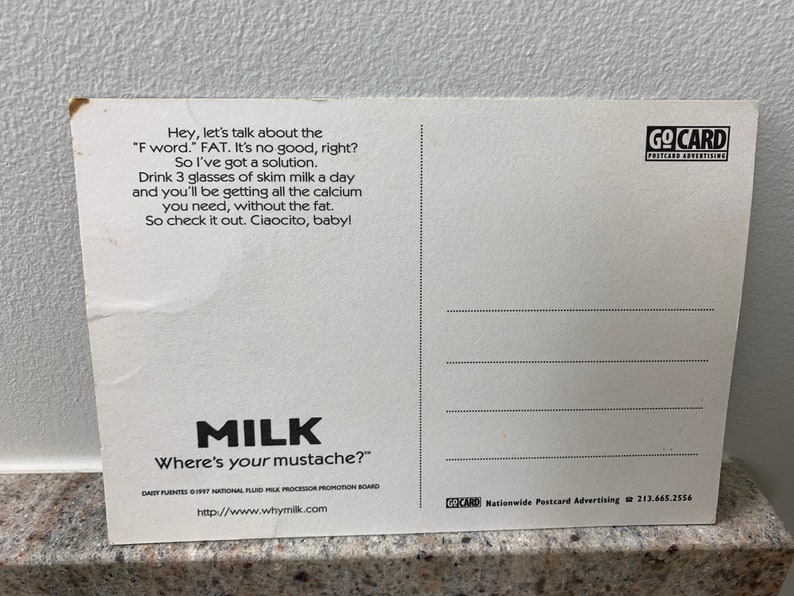 May include: A white postcard with black text that reads "Hey, let's talk about the 'F word.' FAT. It's no good, right? So I've got a solution. Drink 3 glasses of skim milk a day and you'll be getting all the calcium you need, without the fat. So check it out. Ciaocito, baby!"  The postcard also has a logo for "Go Card Postcard Advertising" and a logo for "Milk Where's your mustache?" with the website www.whymilk.com.