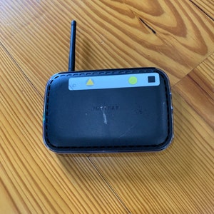 May include: Black wireless router with a single antenna, three yellow lights, and the text "NETGEAR" on the front.